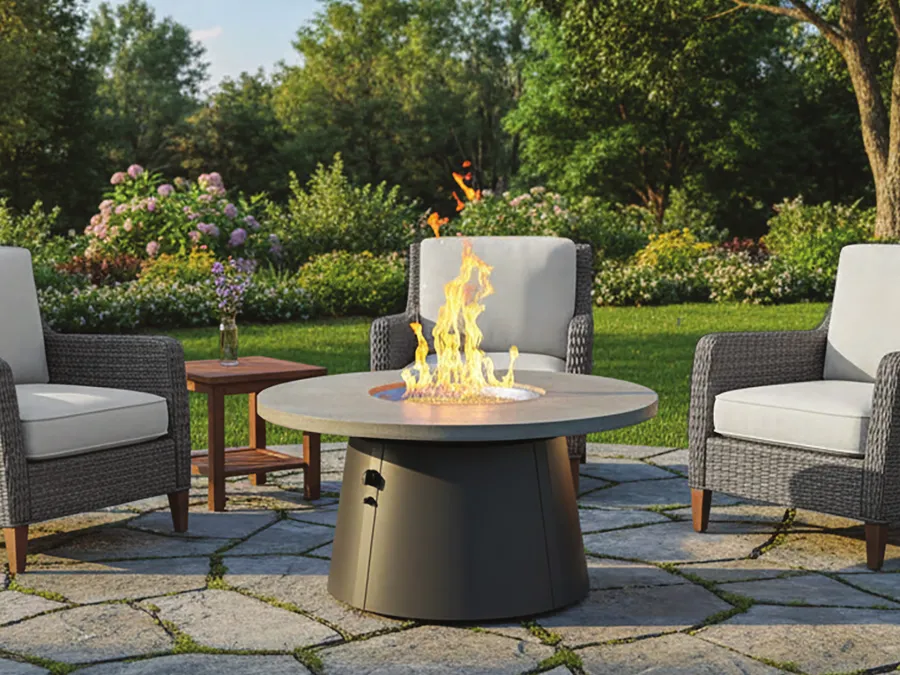 An Outdoor GreatRoom round fire pit table on a flagstone patio