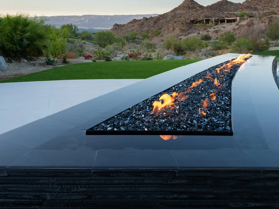 A custom linear fire feature built on The Outdoor Plus burner, overlooking desert hills