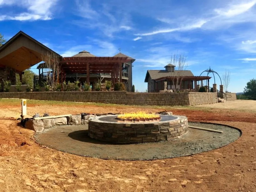 A custom stone fire pit burning on a Warming Trends CROSSFIRE burner