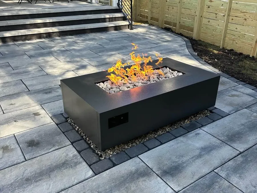 A Warming Trends AON fire table burning on a paver patio