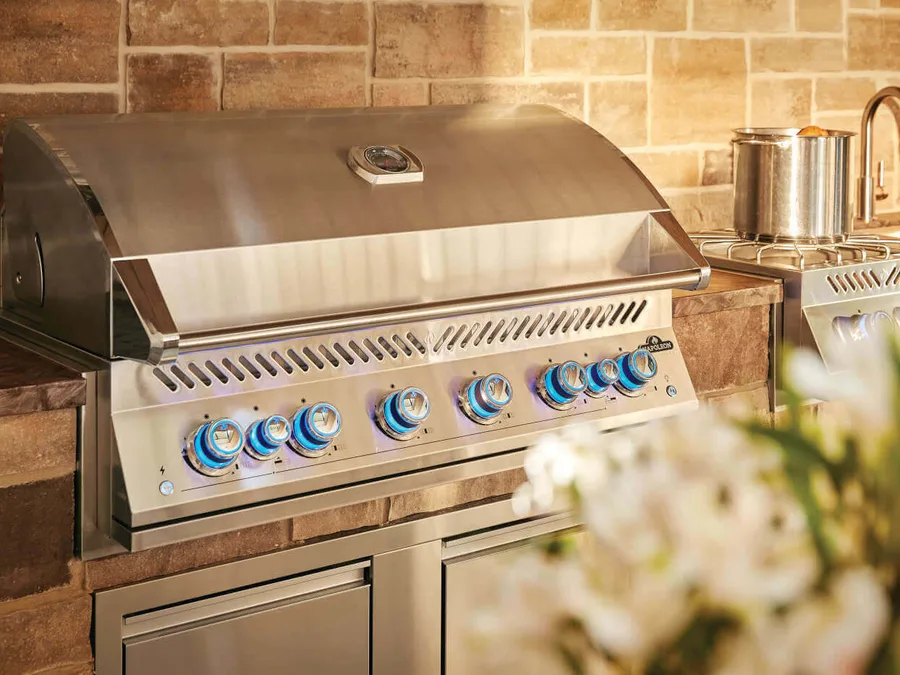 A Napoleon Prestige PRO built-in grill and side burner in a stone outdoor kitchen