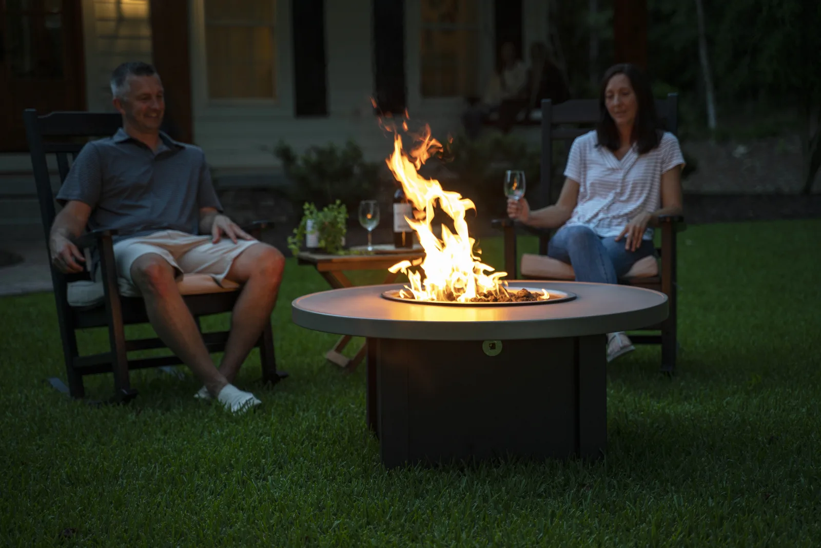 A couple beside a round Stoll fire pit at dusk