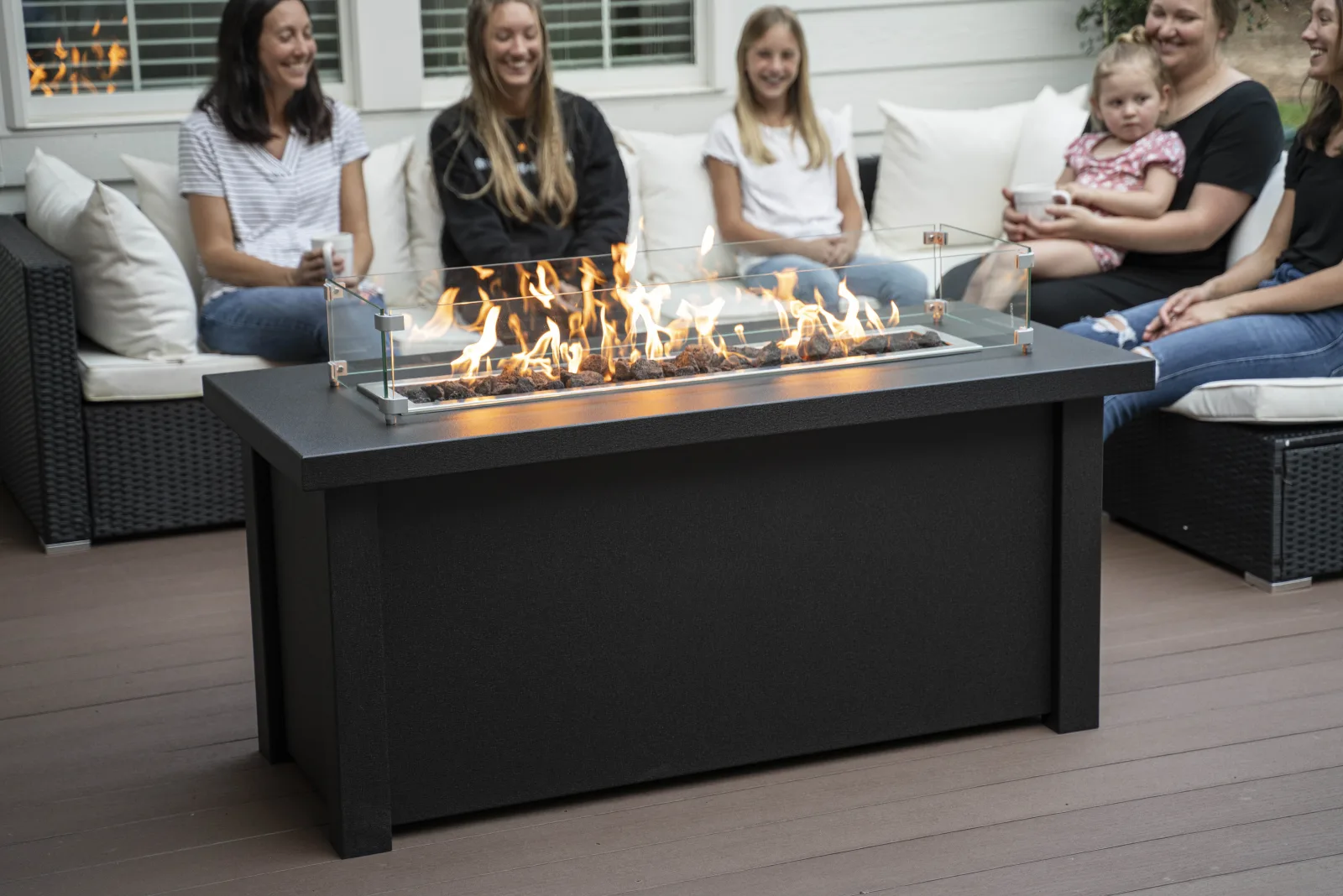 A family gathered around a Stoll linear fire table on a patio